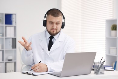 Photo of Doctor in headphones having online consultation via laptop indoors