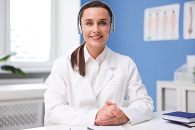 Photo of Doctor in headphones having online consultation indoors