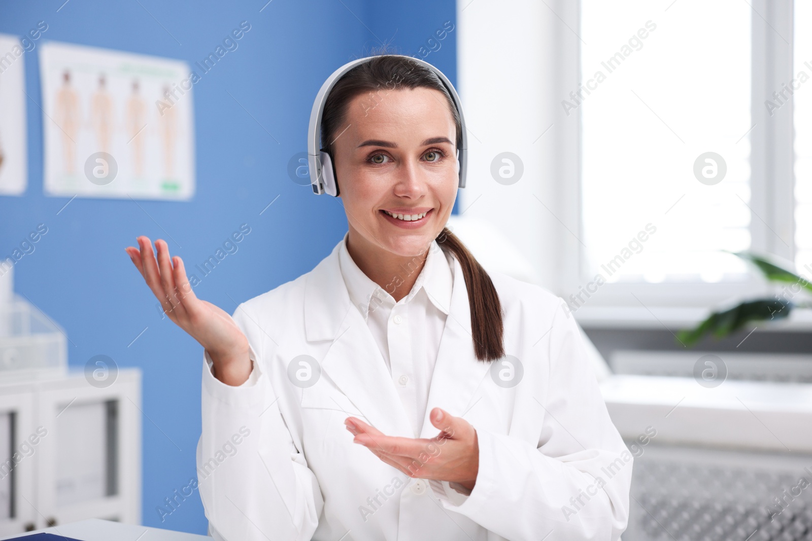 Doctor with headphones having online consultation in clinic Photo of Doctor with headphones having online consultation in clinic