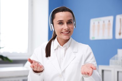 Photo of Doctor with headphones having online consultation in clinic
