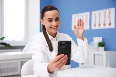 Photo of Doctor having online consultation via smartphone in clinic