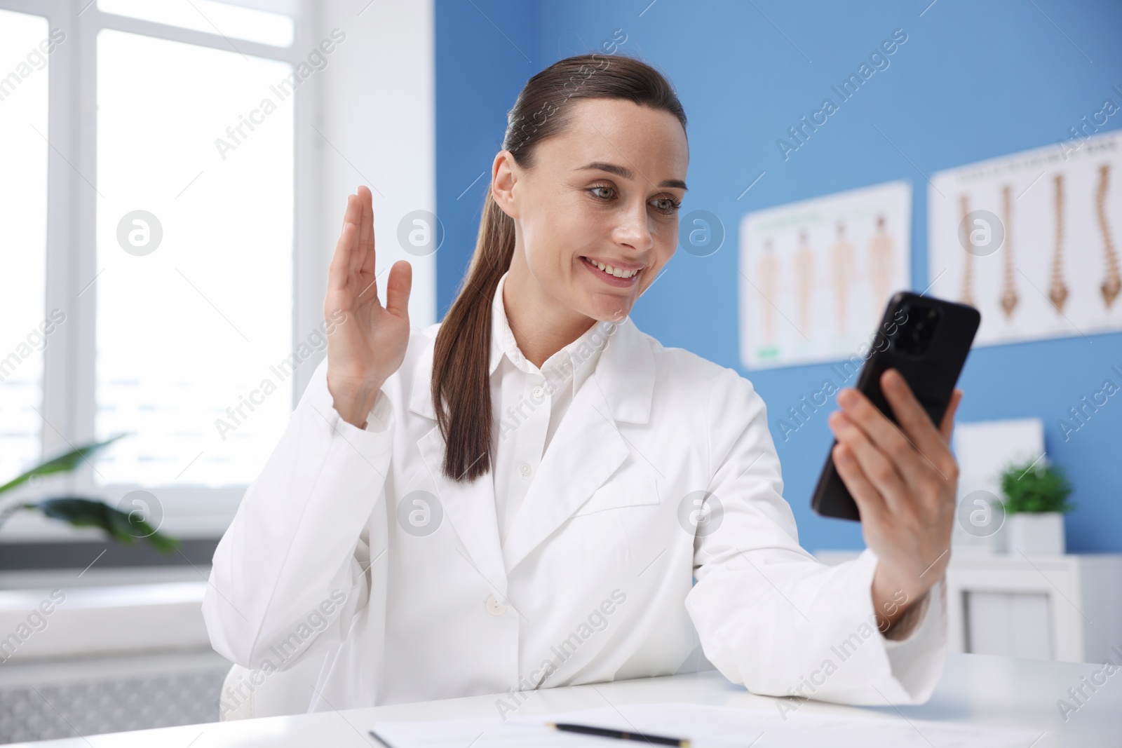 Doctor having online consultation via smartphone in clinic Photo of Doctor having online consultation via smartphone in clinic