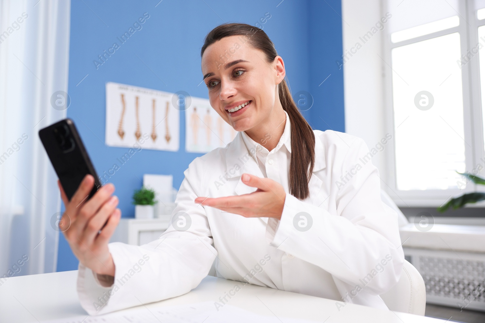 Doctor having online consultation via smartphone in clinic Photo of Doctor having online consultation via smartphone in clinic