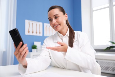 Photo of Doctor having online consultation via smartphone in clinic