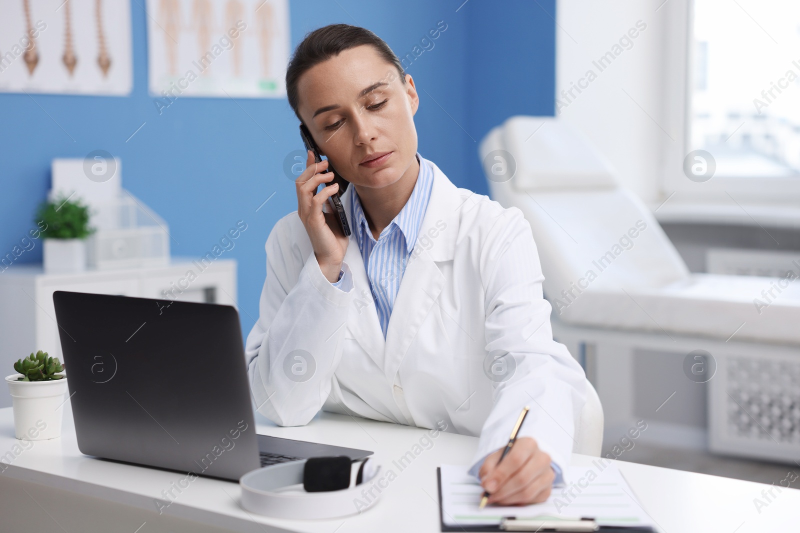 Doctor with smartphone having online consultation at table in clinic Photo of Doctor with smartphone having online consultation at table in clinic