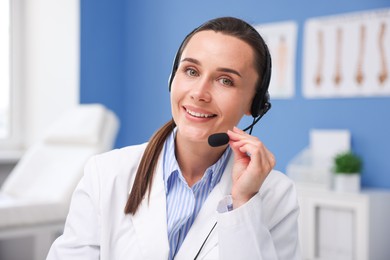 Photo of Doctor with headset having online consultation in clinic