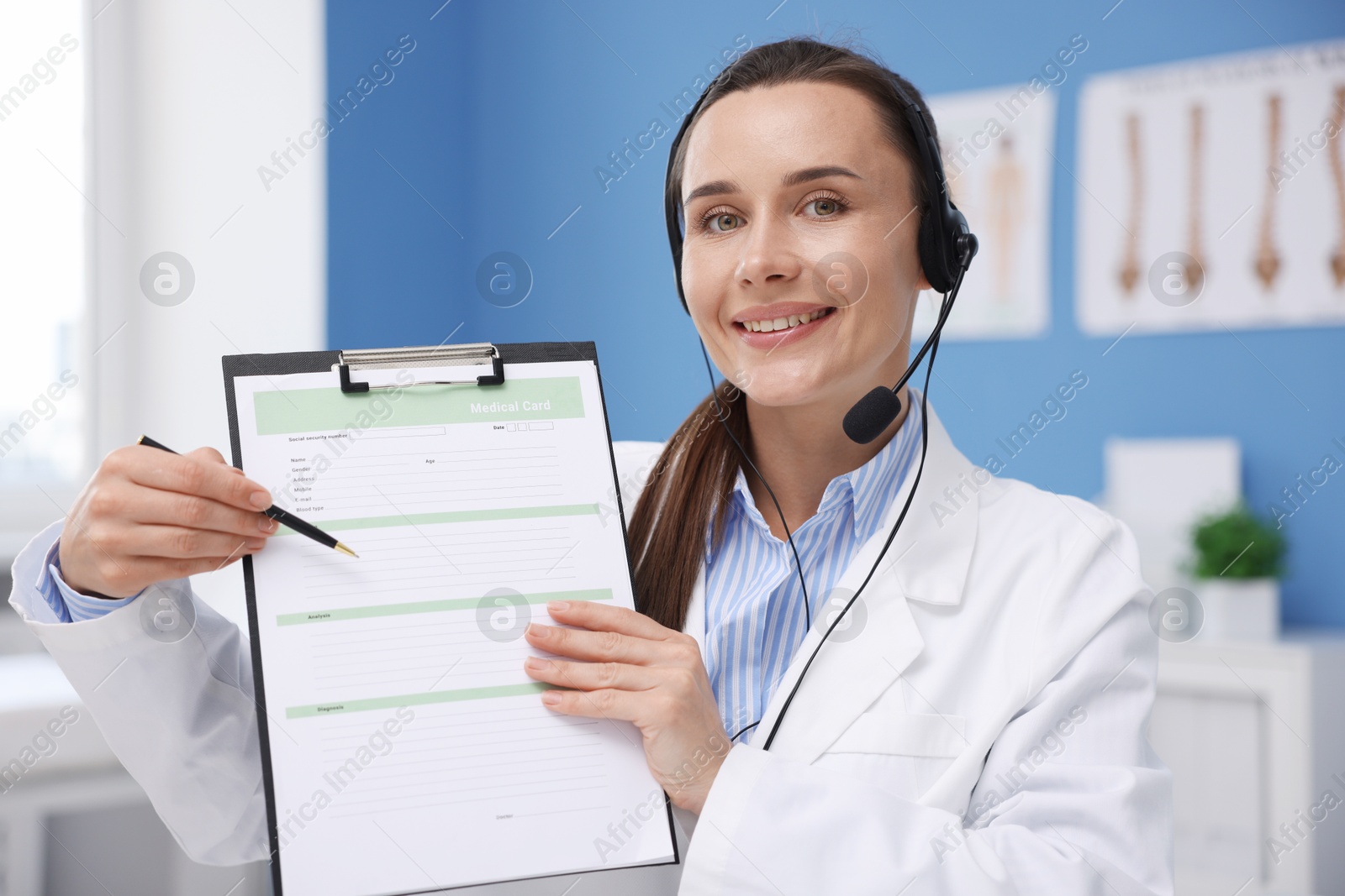 Doctor with headset and clipboard having online consultation in clinic Photo of Doctor with headset and clipboard having online consultation in clinic