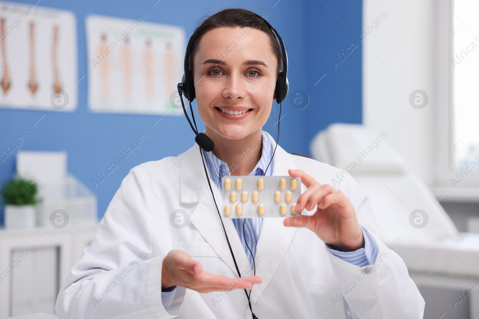 Doctor with headset and pills having online consultation in clinic Photo of Doctor with headset and pills having online consultation in clinic