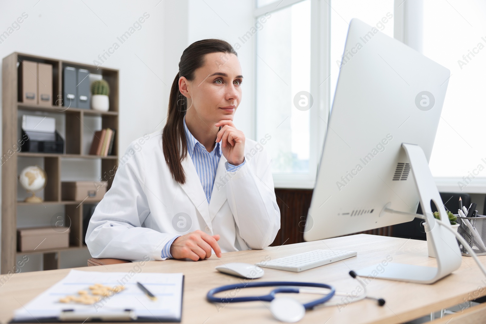 Doctor having online consultation via computer in clinic Photo of Doctor having online consultation via computer in clinic