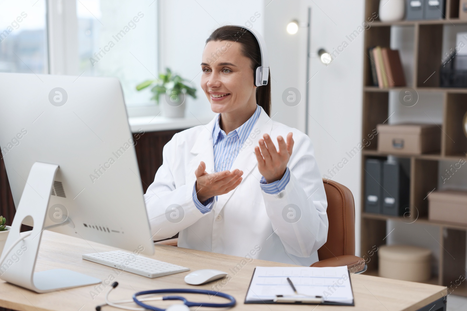 Doctor with headphones having online consultation via computer in clinic Photo of Doctor with headphones having online consultation via computer in clinic