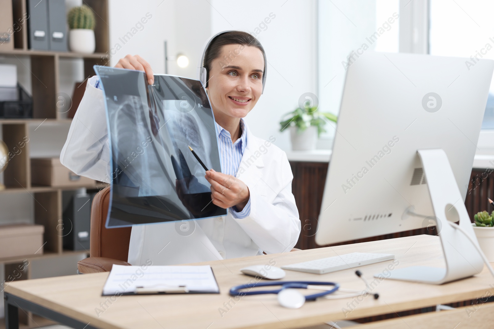 Doctor with lung MRI scan having online consultation via computer in clinic Photo of Doctor with lung MRI scan having online consultation via computer in clinic