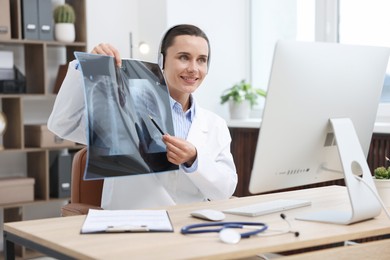 Photo of Doctor with lung MRI scan having online consultation via computer in clinic