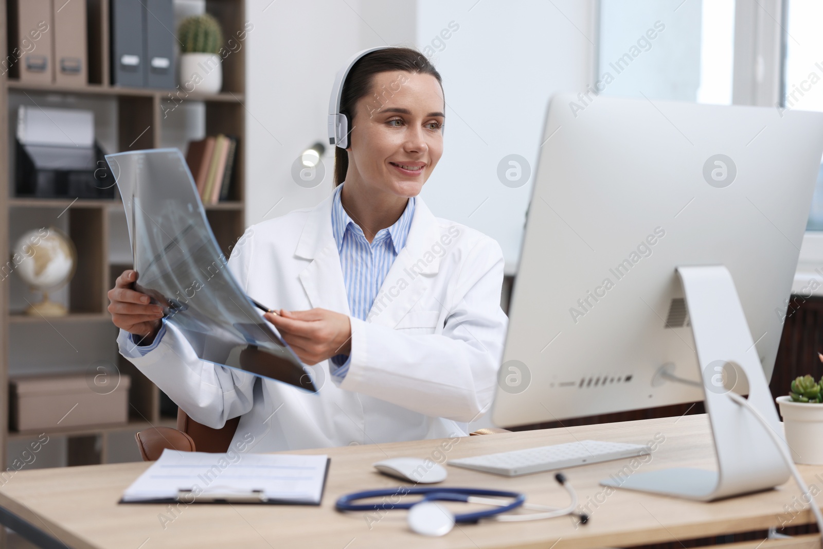 Doctor with lung MRI scan having online consultation via computer in clinic Photo of Doctor with lung MRI scan having online consultation via computer in clinic