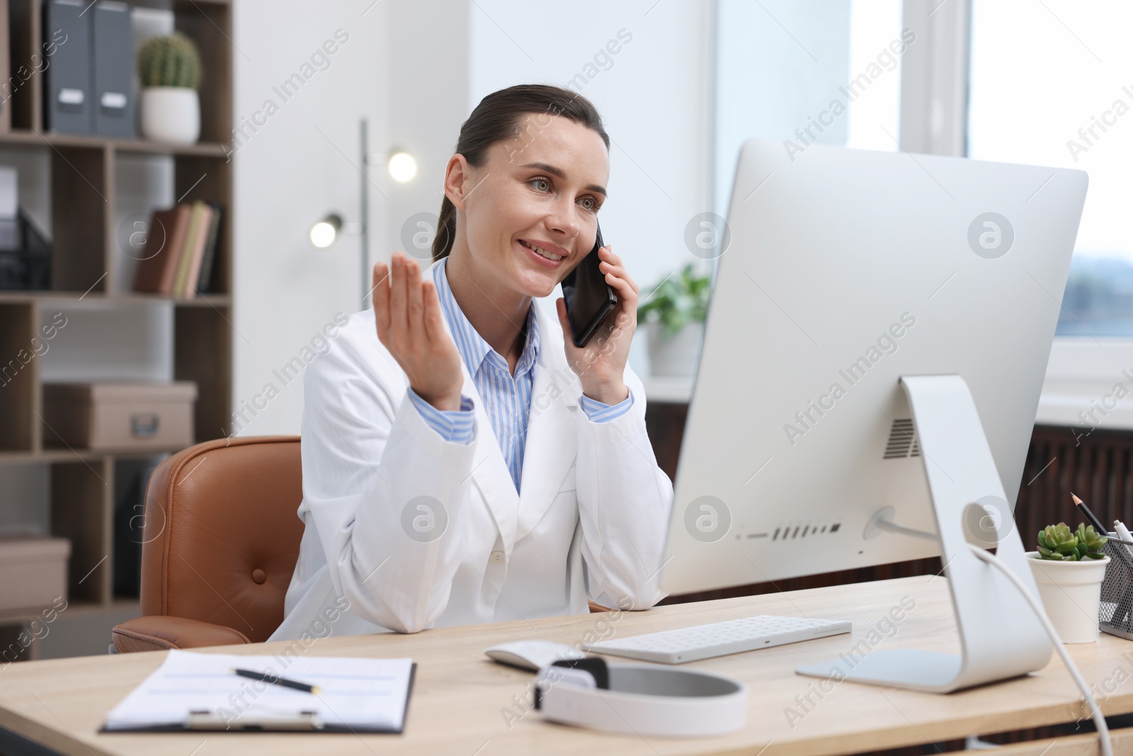 Doctor with smartphone having online consultation in clinic Photo of Doctor with smartphone having online consultation in clinic