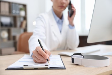 Photo of Doctor with smartphone having online consultation in clinic, selective focus