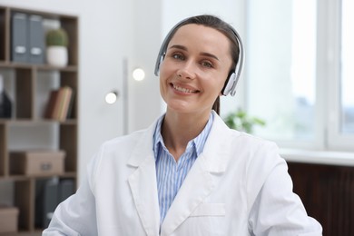 Photo of Doctor with headphones having online consultation in clinic