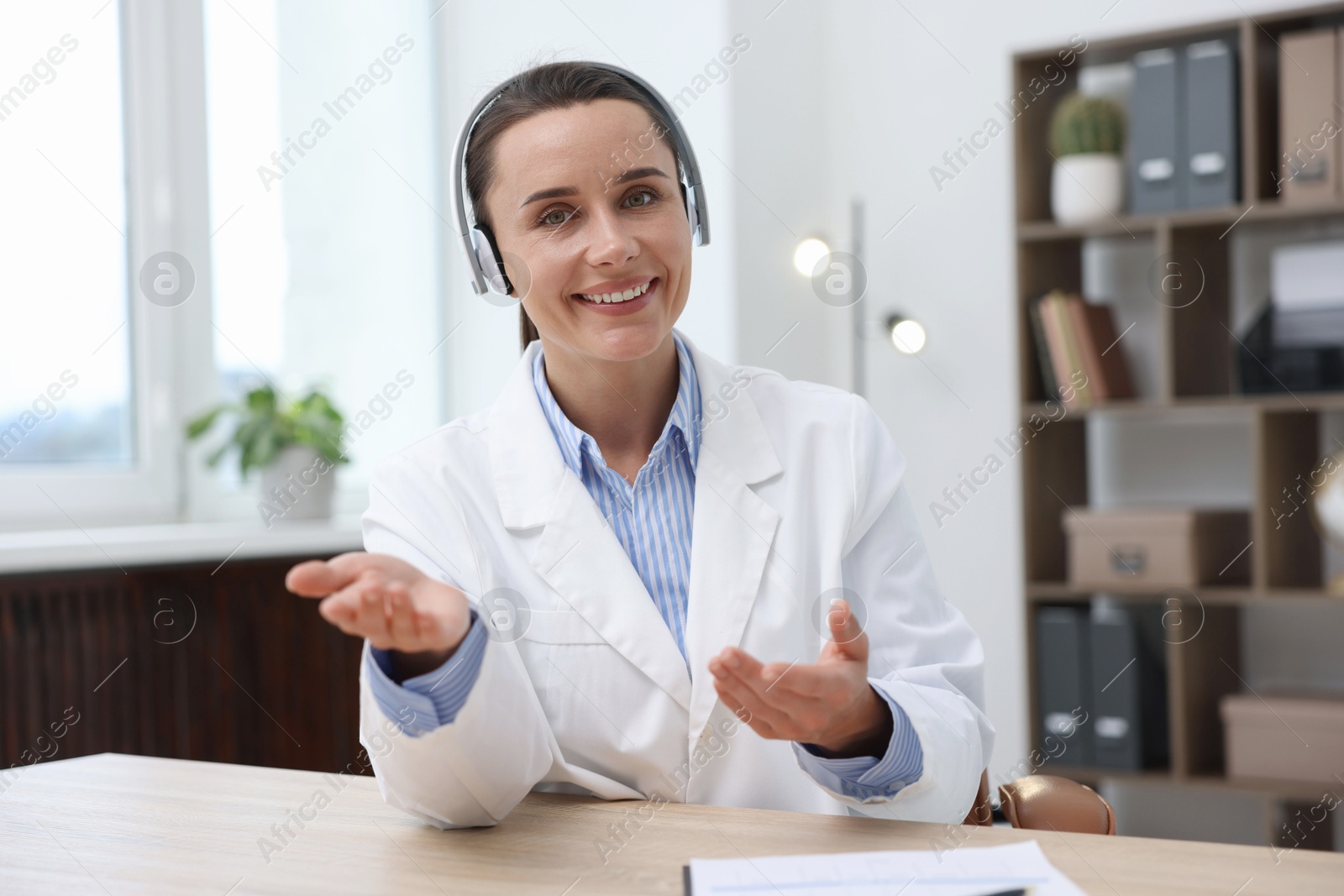 Doctor in headphones having online consultation at table indoors Photo of Doctor in headphones having online consultation at table indoors