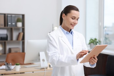 Photo of Doctor using tablet in clinic, space for text. Online medical consultation