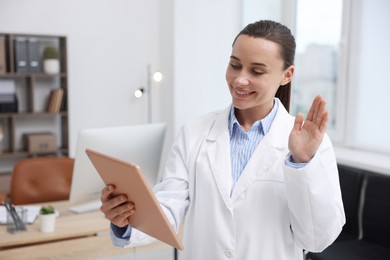 Photo of Doctor with tablet having online consultation in clinic