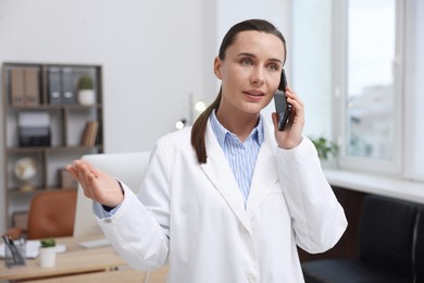 Photo of Doctor with smartphone having online consultation in clinic