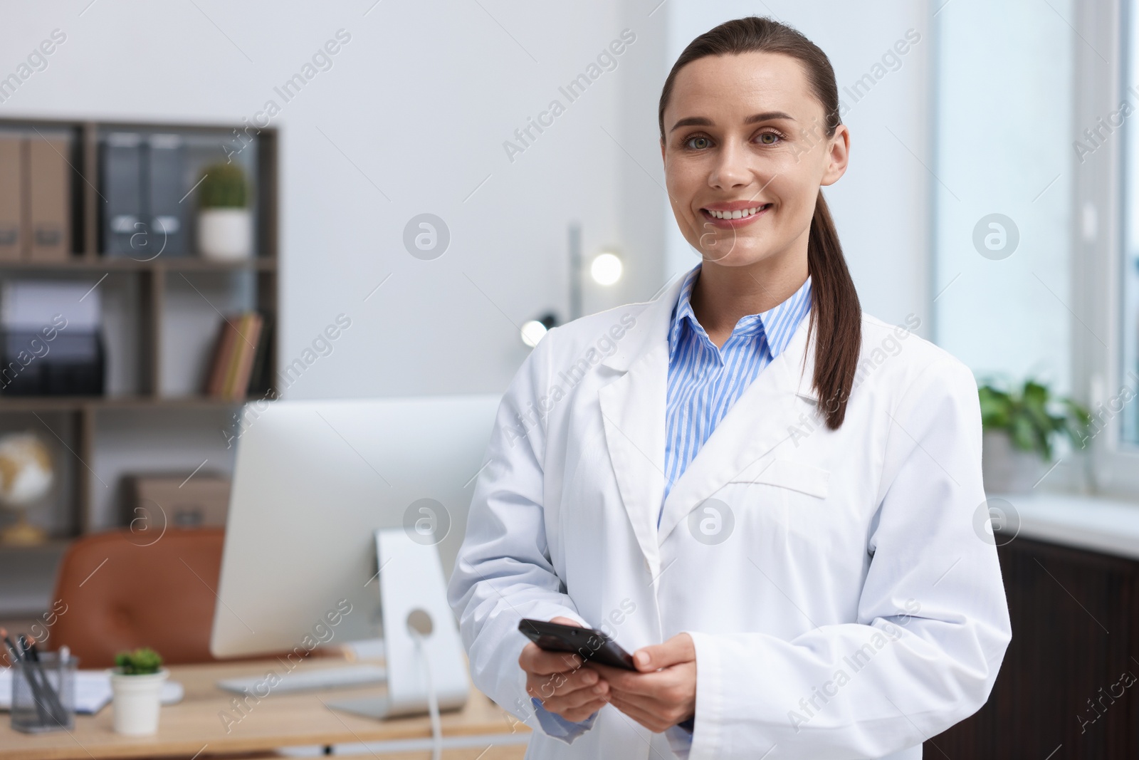 Doctor with smartphone in clinic, space for text. Online medical consultation Photo of Doctor with smartphone in clinic, space for text. Online medical consultation