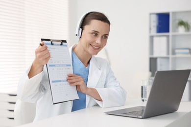 Photo of Doctor in headphones having online consultation via laptop indoors