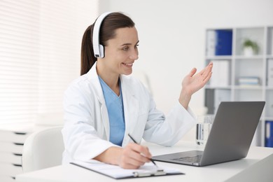 Photo of Doctor in headphones having online consultation via laptop indoors