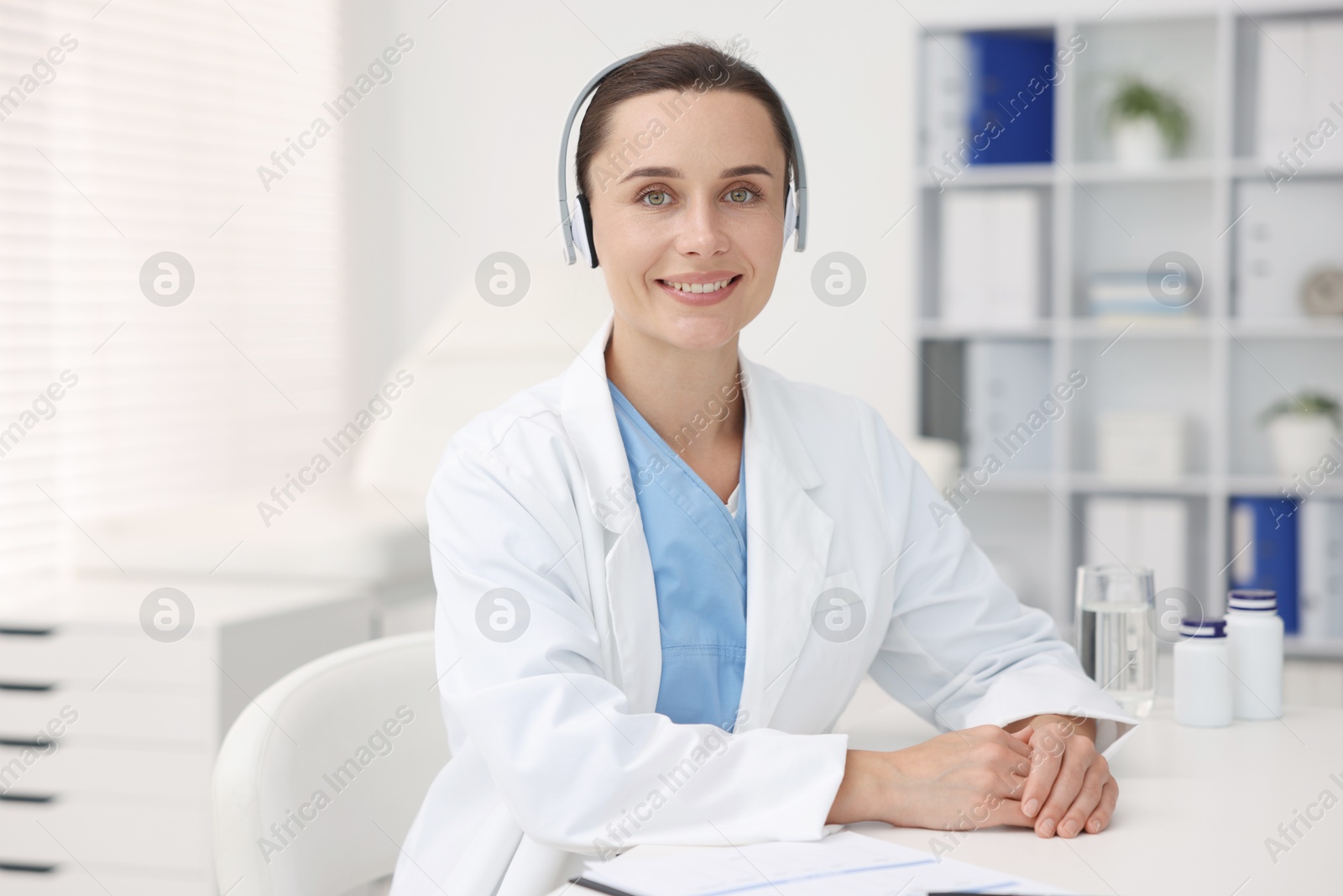 Doctor in headphones at table indoors. Online medical consultation Photo of Doctor in headphones at table indoors. Online medical consultation