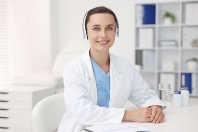 Photo of Doctor in headphones at table indoors. Online medical consultation