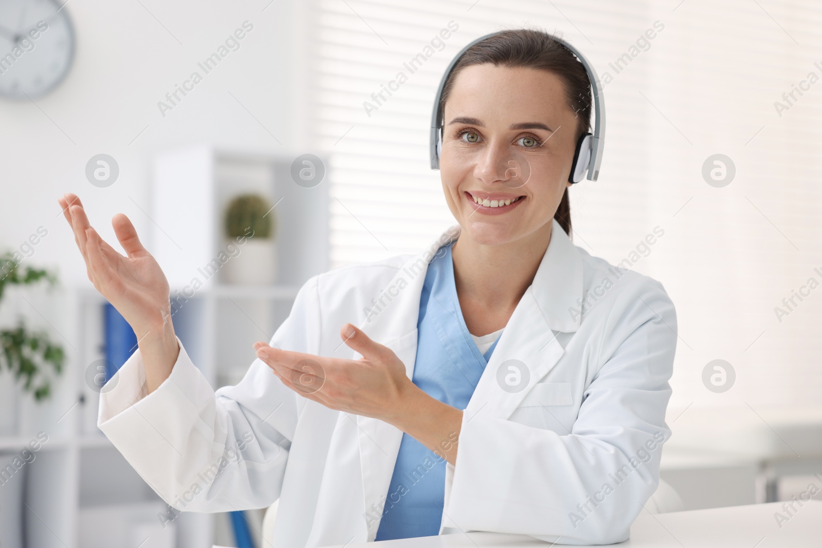 Doctor in headphones at table indoors. Online medical consultation Photo of Doctor in headphones at table indoors. Online medical consultation