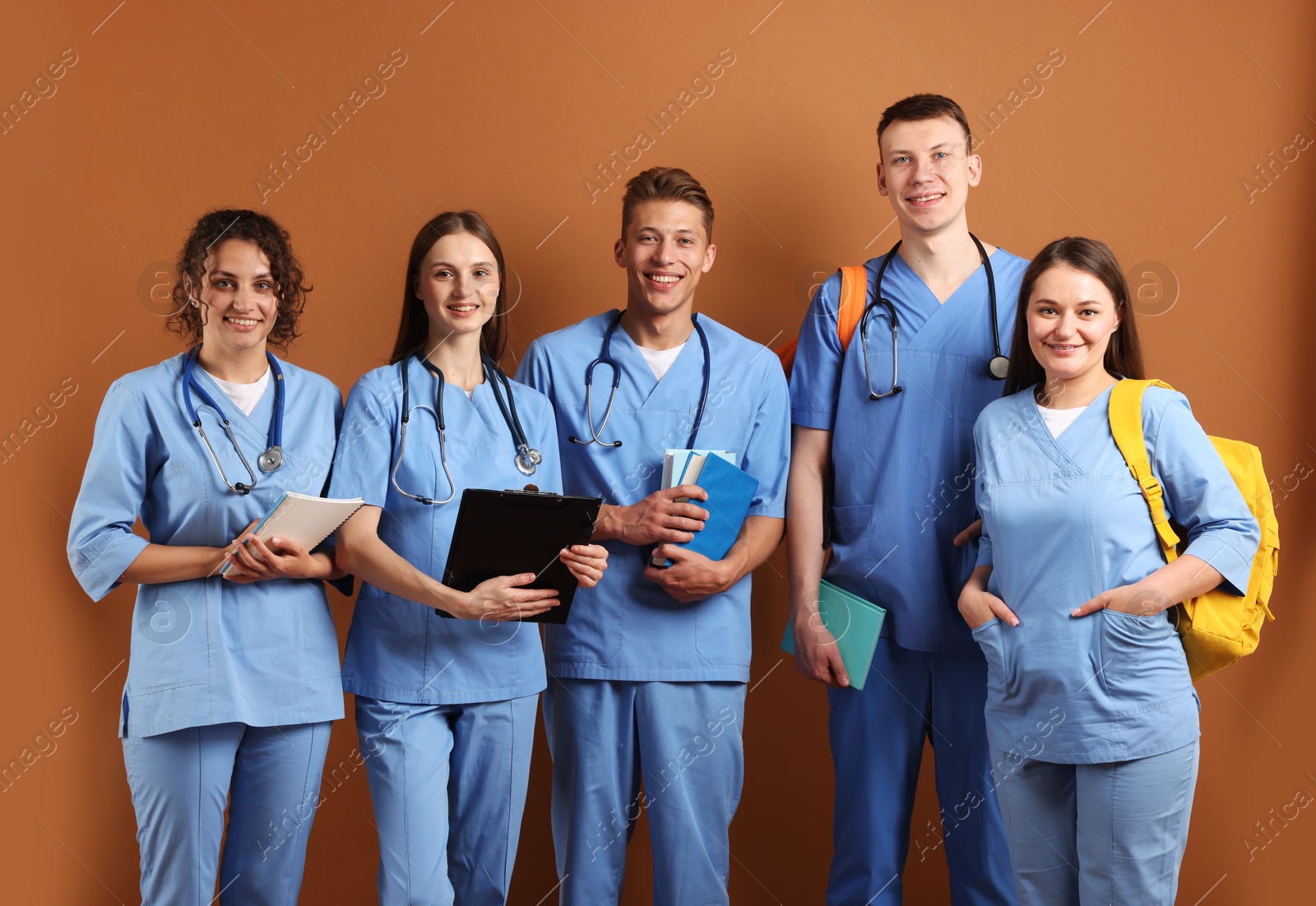 Group of medical students with books on brown background Photo of Group of medical students with books on brown background