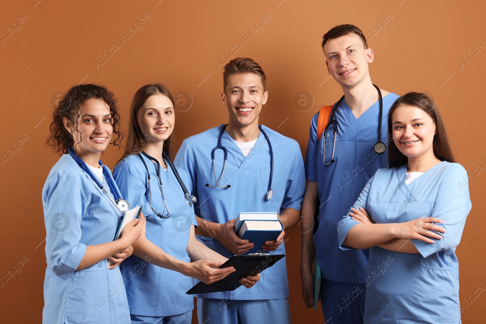 Group of medical students with books on brown background Photo of Group of medical students with books on brown background