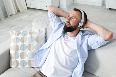 Photo of Harmony. Man listening to music in headphones on sofa at home