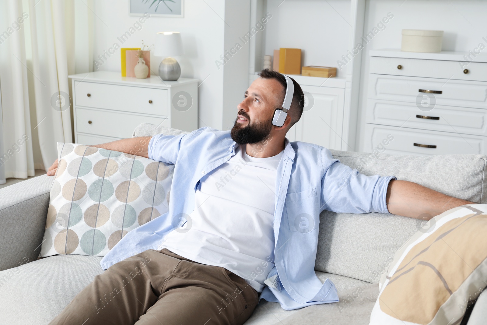 Harmony. Man listening to music in headphones on sofa at home Photo of Harmony. Man listening to music in headphones on sofa at home