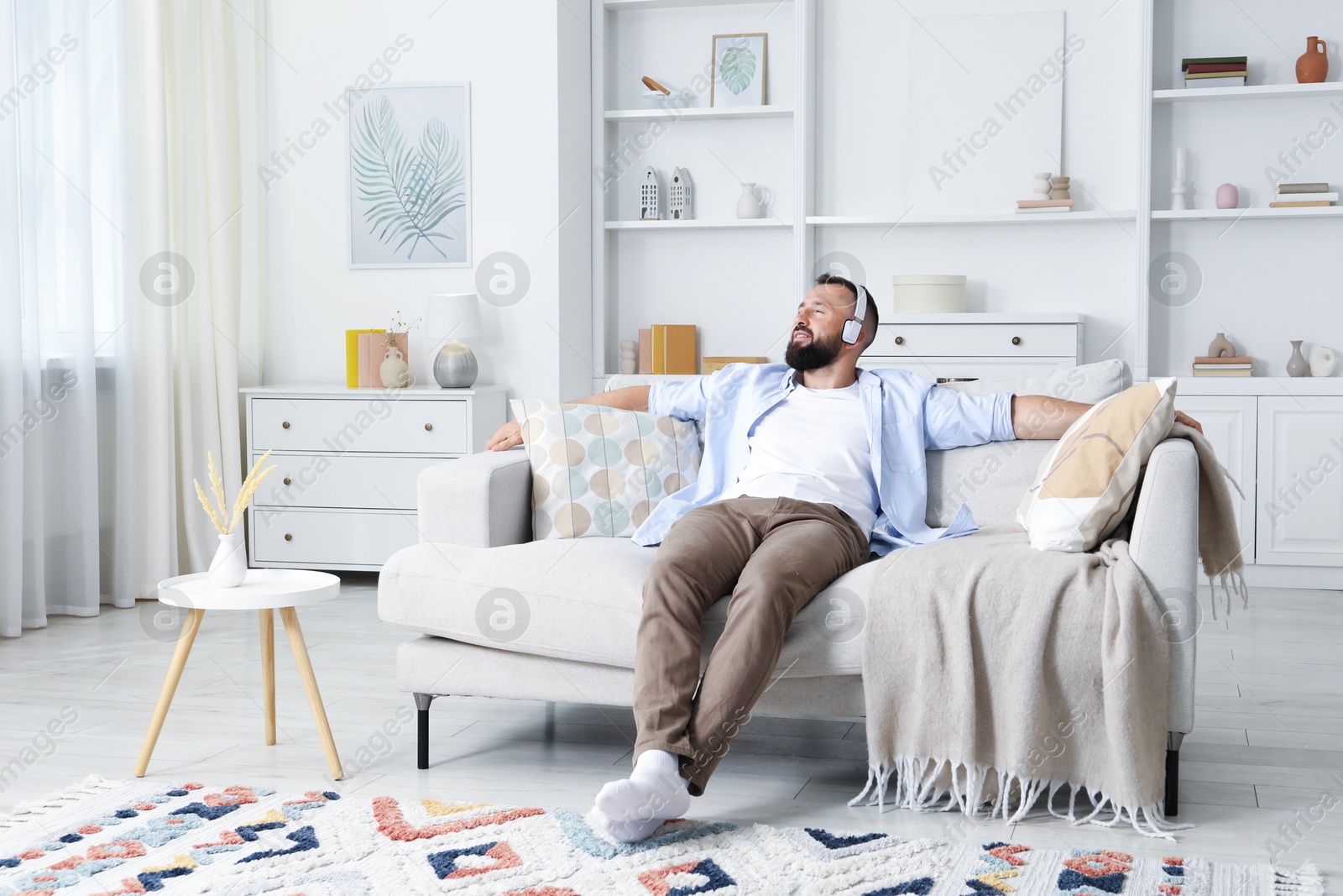 Harmony. Man listening to music in headphones on sofa at home Photo of Harmony. Man listening to music in headphones on sofa at home