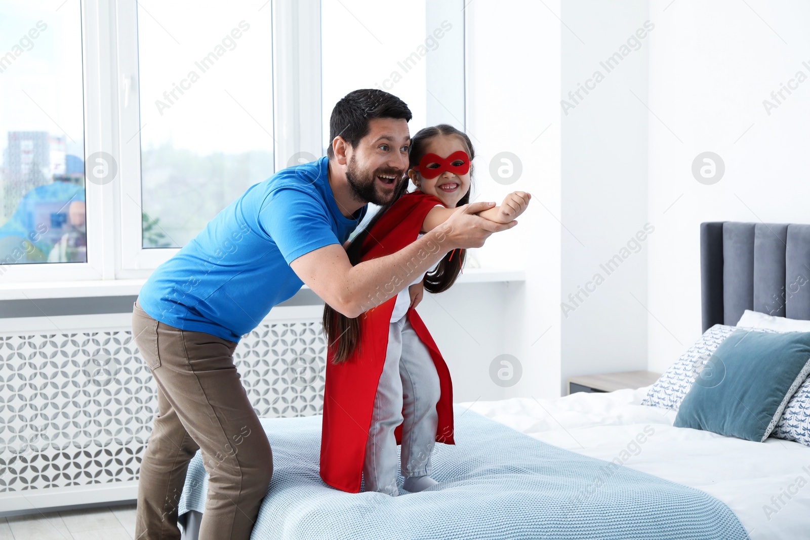 Father and his daughter in superhero costume playing at home Photo of Father and his daughter in superhero costume playing at home