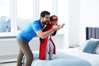 Photo of Father and his daughter in superhero costume playing at home