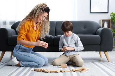 Photo of Mother and her son playing with wooden constructor blocks on floor at home