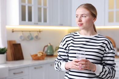 Photo of Young woman with glass of water in kitchen. Space for text