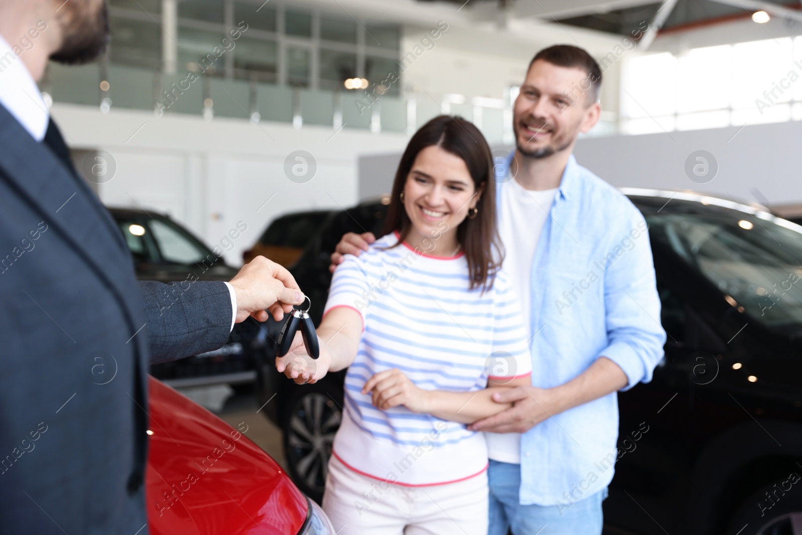 Salesman giving car key to happy family in salon, selective focus Photo of Salesman giving car key to happy family in salon, selective focus