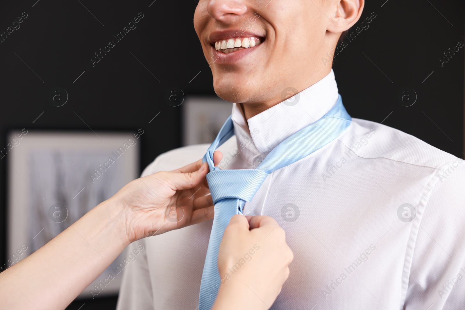 Woman tying man's necktie at home, closeup Photo of Woman tying man's necktie at home, closeup