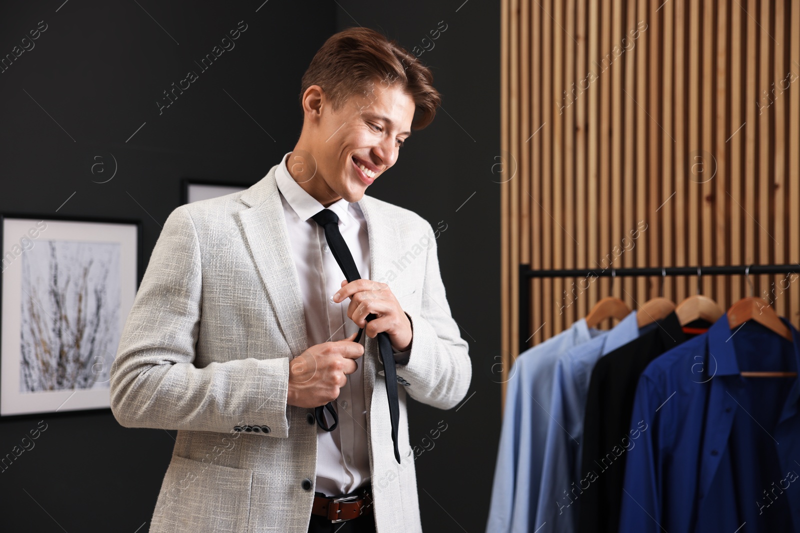 Man tying stylish black necktie at home Photo of Man tying stylish black necktie at home
