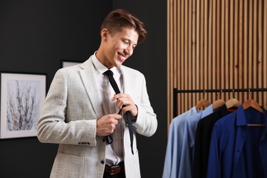Photo of Man tying stylish black necktie at home