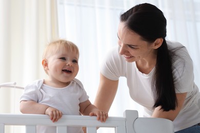 Photo of Mother playing with her cute baby in crib at home