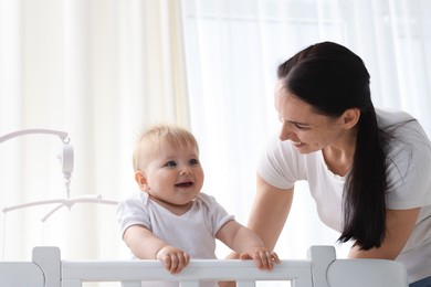 Photo of Mother playing with her cute baby in crib at home