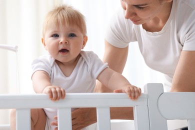 Photo of Mother playing with her cute baby in crib at home