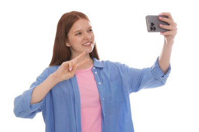 Photo of Smiling teenage girl taking selfie by smartphone and showing peace sign on white background