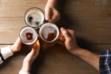 Photo of Friends with glasses of beer at wooden table, top view