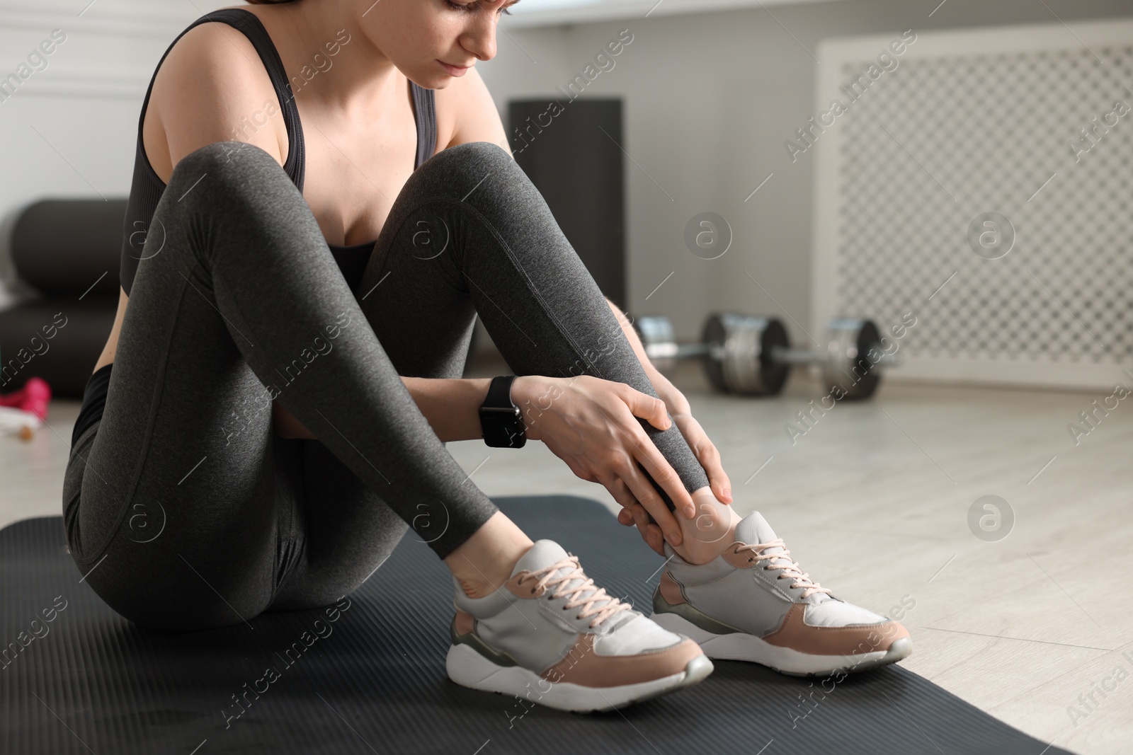 Sports injury. Young woman suffering from leg pain in fitness studio, closeup Photo of Sports injury. Young woman suffering from leg pain in fitness studio, closeup