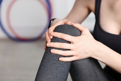 Photo of Sports injury. Young woman suffering from knee pain in fitness studio, closeup. Space for text